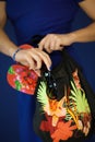 Beautiful woman in blue dress holding beach paraphernalia in her hands, like flip flops, sunglasses and beach bag