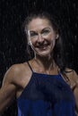 Beautiful woman in blue dress stands in rain at night