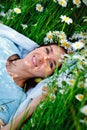 A beautiful woman in a blue dress and a wreath of flowers lies on a field with chamomiles. Enjoys nature and summer time in the Royalty Free Stock Photo