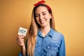 Beautiful woman with blue eyes celebrating 8th march womens day holding reminder paper with a happy face standing and smiling with