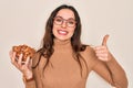 Beautiful woman with blue eyes holding bowl with healthy almonds over white background happy with big smile doing ok sign, thumb Royalty Free Stock Photo