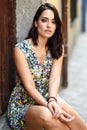 Beautiful woman with blue eyes sitting on urban step. Girl wearing flower dress outdoors. Beauty and fashion concept Royalty Free Stock Photo