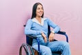 Beautiful woman with blue eyes sitting on wheelchair looking away to side with smile on face, natural expression Royalty Free Stock Photo