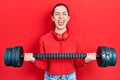 Beautiful woman with blue eyes wearing sportswear using dumbbells sticking tongue out happy with funny expression Royalty Free Stock Photo