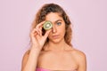 Beautiful woman with blue eyes wearing towel shower after bath holding kiwi fruit over eye with a confident expression on smart Royalty Free Stock Photo