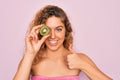 Beautiful woman with blue eyes wearing towel shower after bath holding kiwi fruit over eye happy with big smile doing ok sign, Royalty Free Stock Photo