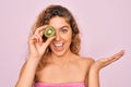 Beautiful woman with blue eyes wearing towel shower after bath holding kiwi fruit over eye very happy and excited, winner Royalty Free Stock Photo