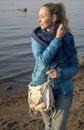 Beautiful woman in a blue jacket and jeans on the sandy shore of the Gulf of Finland, Russia, Petersburg,soft focus Royalty Free Stock Photo