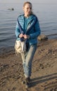 Beautiful woman in a blue jacket and jeans on the sandy shore of the Gulf of Finland, Russia, Petersburg,soft focus Royalty Free Stock Photo