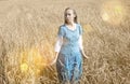 Beautiful woman in a blue long dress in the field of ripe cereals