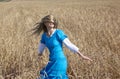 Beautiful woman in a blue long dress in the field of ripe cereals