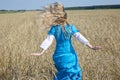 Beautiful woman in a blue long dress in the field of ripe cereals