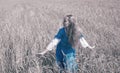 Beautiful woman in a blue long dress in the field of ripe cereals, toning