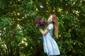 Beautiful woman in a blue summer dress with lilac flowers in a blooming garden. Spring Blossom Royalty Free Stock Photo