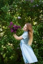 Beautiful woman in a blue summer dress with lilac flowers in a blooming garden. Spring Blossom Royalty Free Stock Photo