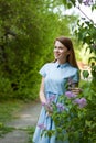 Beautiful woman in a blue summer dress with lilac flowers in a blooming garden. Spring Blossom Royalty Free Stock Photo