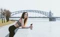 1 beautiful woman with a bottle of water in her hands stands on the embankment and looks at the river, The bridge over the Royalty Free Stock Photo