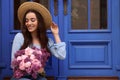 Beautiful woman with bouquet of spring flowers near blue wooden doors, space for text Royalty Free Stock Photo