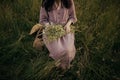 Beautiful woman with bouquet of wildflowers sitting barefoot on chair among grass in summer meadow Royalty Free Stock Photo