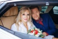 Beautiful woman bride with a bouquet of flowers and a man sitting in the car, looking out the window Royalty Free Stock Photo