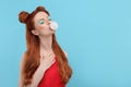 Beautiful woman with bright makeup and closed eyes blowing bubble gum on light blue background. Space for text Royalty Free Stock Photo