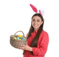 Beautiful woman in bunny ears headband holding basket with Easter eggs on white Royalty Free Stock Photo