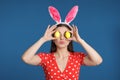 Beautiful woman in bunny ears headband holding Easter eggs near eyes Royalty Free Stock Photo