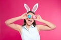 Beautiful woman in bunny ears headband holding Easter eggs near eyes on background Royalty Free Stock Photo