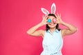 Beautiful woman in bunny ears headband holding Easter eggs near eyes on color background Royalty Free Stock Photo