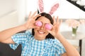 Beautiful woman in bunny ears headband holding Easter eggs near eyes Royalty Free Stock Photo