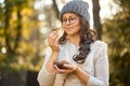 Woman in cap and glasses is holding mushrooms in hands in autumn forest