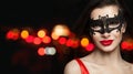 Beautiful woman in carnival mask on black night background with abstract bokeh glitter Royalty Free Stock Photo