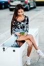 Beautiful woman charging her phone on free multipurpose solar panel charger incorporated in to sitting bench for citizens.Modern t Royalty Free Stock Photo