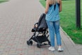 Beautiful woman with a child in a pram walks through a summer park. Royalty Free Stock Photo