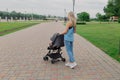 Beautiful woman with a child in a pram walks through a summer park. Royalty Free Stock Photo