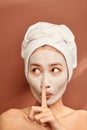 Beautiful woman with clay facial mask over orange background. Beauty treatment and spa concept Royalty Free Stock Photo