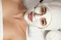 Beautiful woman with a clay mask on her face. Facial peeling mask. Spa skin and body care. Female facial of beauty treatment. Royalty Free Stock Photo