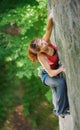 Beautiful woman climber climbing steep rock with rope