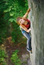 Beautiful woman climber climbing steep rock with rope