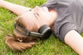 Beautiful woman in closeup lying on grass and listen music