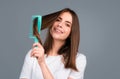 Beautiful woman combs her healthy hair. Combing healthy long straight female hair, close up. Attractive gorgeous Royalty Free Stock Photo