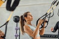 Beautiful woman concentrated with suspension strap workout at gym hiit class. Royalty Free Stock Photo