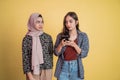 a beautiful woman confidently using a mobile phone and a woman in veil beside her looking suspiciously