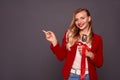 Beautiful woman with cosmetic brushes with red ribbon isolated on grey background. Concept of hand point finger to copy space Royalty Free Stock Photo