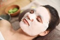 Beautiful woman with cotton mask sheet on face relaxing in spa salon Royalty Free Stock Photo