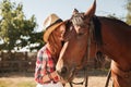 Beautiful woman cowgirl standing and kissing her horse Royalty Free Stock Photo