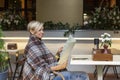 A beautiful woman in a cozy blanket at a table in a street cafe reads the menu. Relaxation in the city