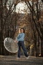 Beautiful woman with curly hair dance in alley of autumn park. Girl holds transparent umbrella and laughs