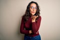 Beautiful woman with curly hair wearing casual sweater and glasses over white background looking at the camera blowing a kiss with Royalty Free Stock Photo