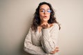 Beautiful woman with curly hair wearing casual sweater and glasses over white background looking at the camera blowing a kiss with Royalty Free Stock Photo